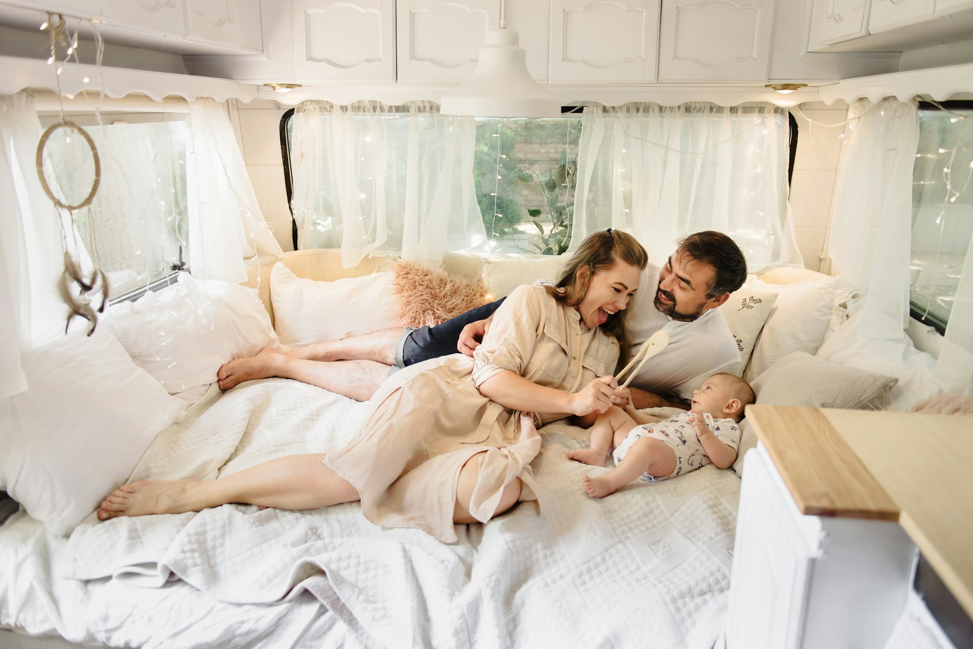 Family with baby on the bed in trailer in the morning.