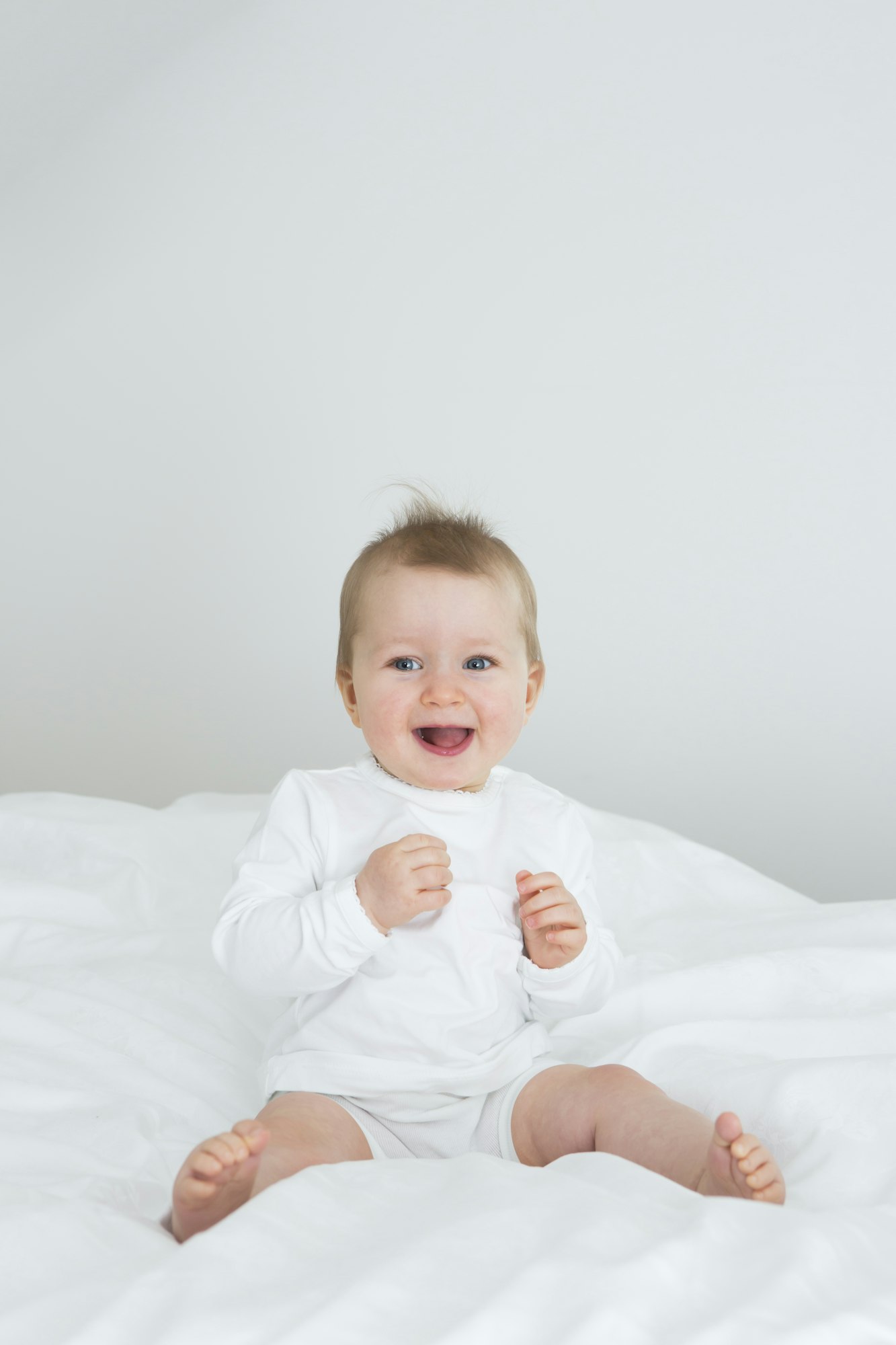 Smiling baby girl sitting on bed